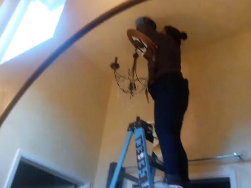 Electrician installing a chandelier in a Mukwonago residence